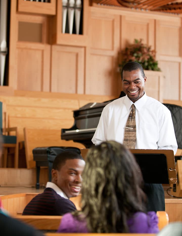 A church speaker shares a message with congregants seated in a sanctuary.